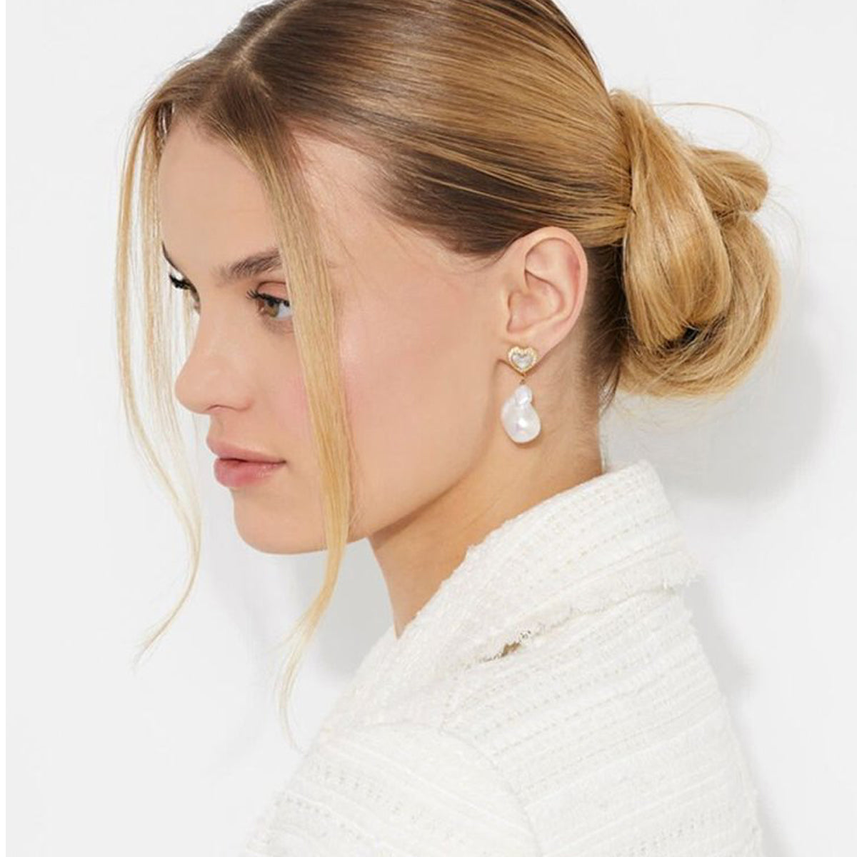 Woman wearing elegant earrings, styled with GUESS JEWELS JEWELRY Mod. JUBE04022JWYGWHT-U for a chic look.