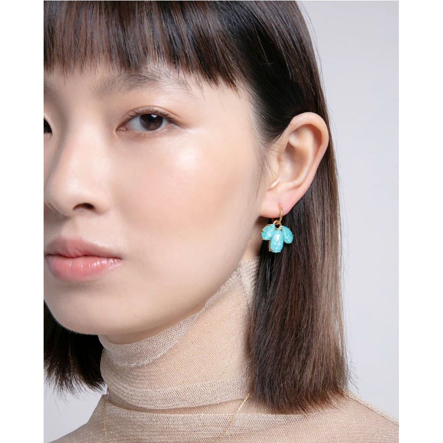Woman wearing silver earrings with blue gemstones, showcases stylish jewelry fashion on a model.