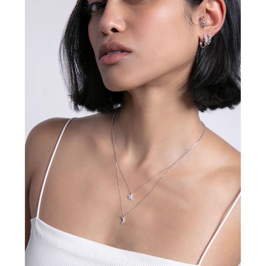 Woman wearing layered necklaces and earrings, showcasing elegant silver jewelry.