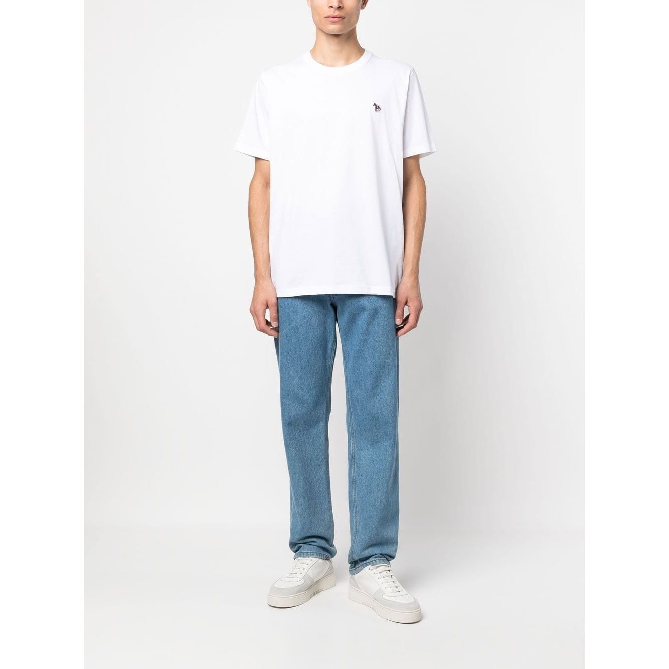 Man wearing PS By Paul Smith T-shirts and Polos White, featuring short sleeves, crew neck, zebra logo, with blue jeans and white sneakers.
