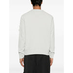 Back view of model wearing C.P. COMPANY Sweaters Clear Blue with ribbed cuffs and hem, sleeve patch pocket, and crew neck design.