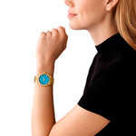 Woman wearing MICHAEL KORS Mod. LENNOX gold wristwatch, 39mm case, blue dial, showcasing elegant quartz design on wrist.