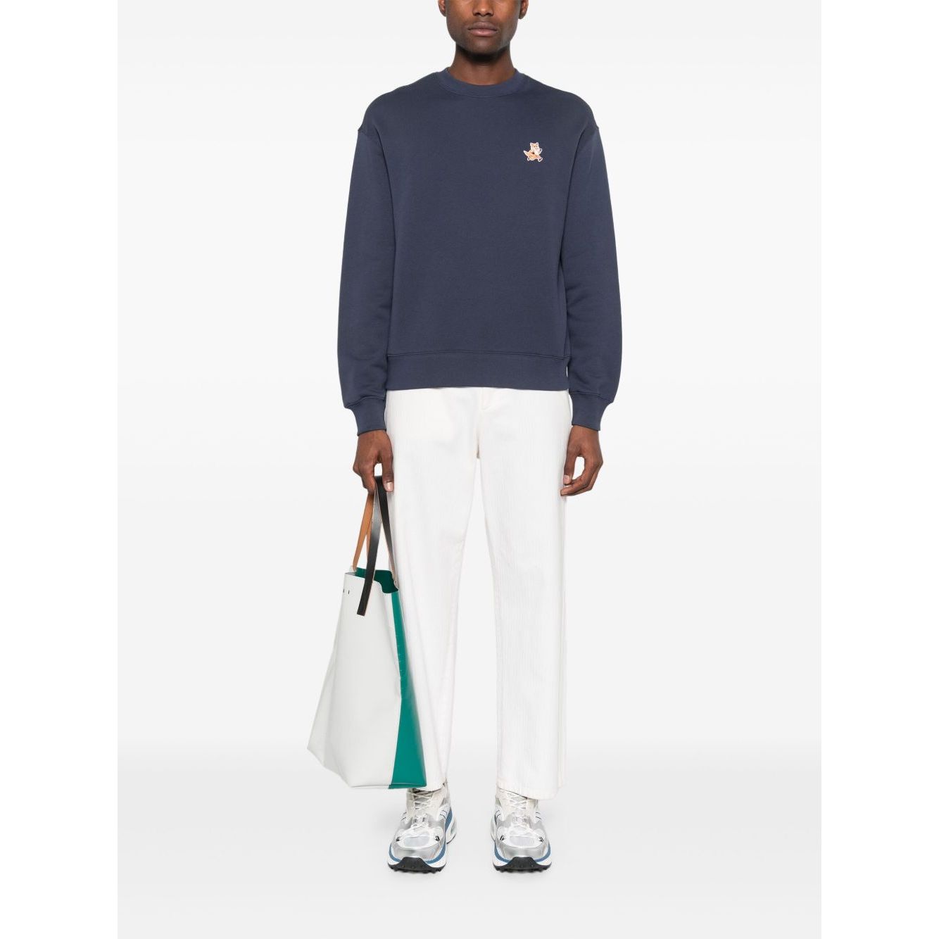 Model wearing Maison Kitsuné Maison Kitsune fox-motif cotton sweatshirt in navy blue with ribbed cuffs and hem, holding a white tote bag.