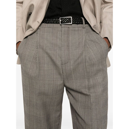 Close-up of person wearing plaid trousers with black belt and beige blazer. Fashionable office attire showcasing classic style.